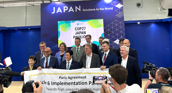 Fourteen people are standing on a stage holding a banderoll with the text: Paris Agreement Article 6 Implementation Partnership