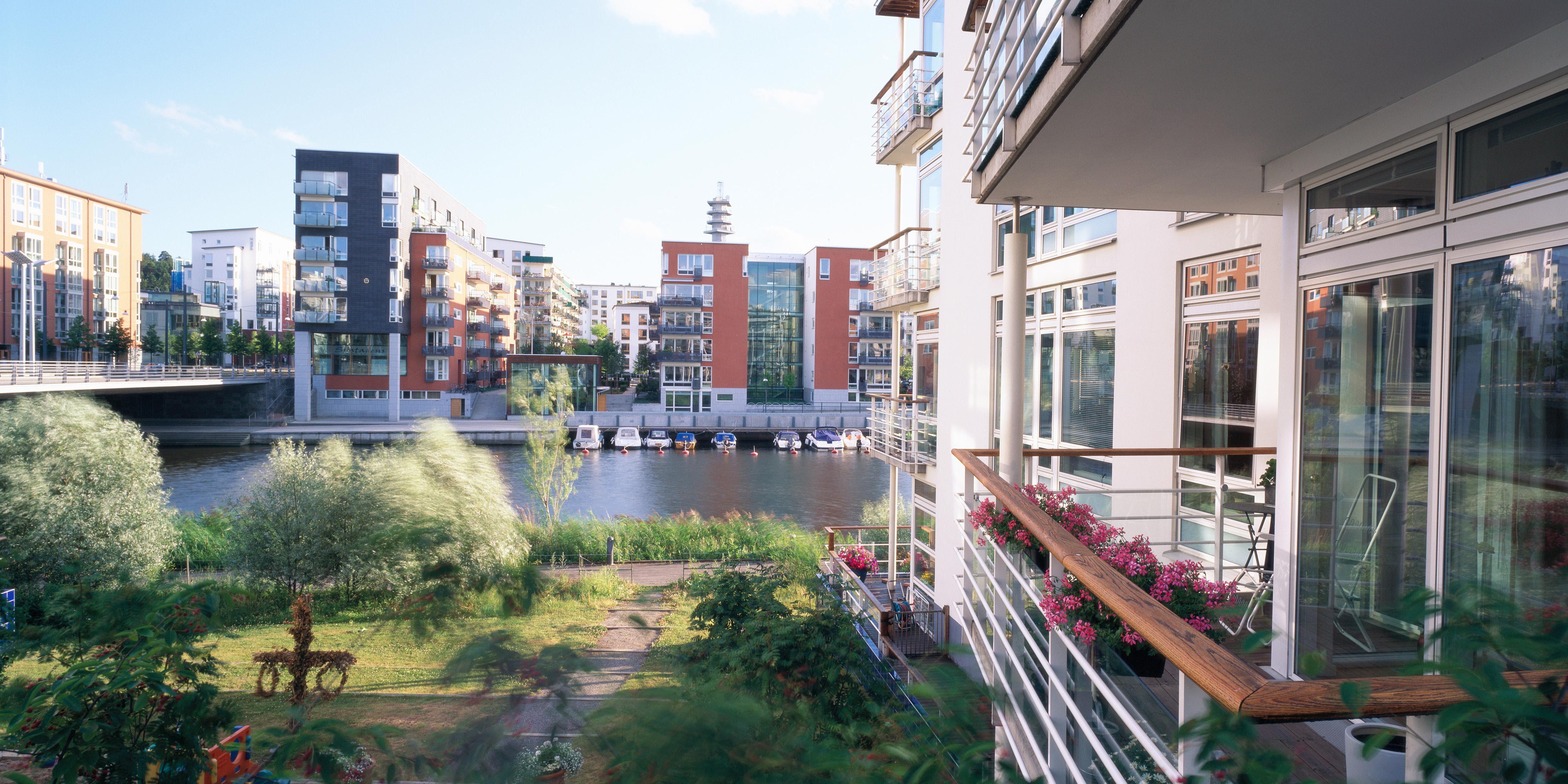 Byggnader vid en hamn med sm&aring;b&aring;tar och l&auml;genhetshus.