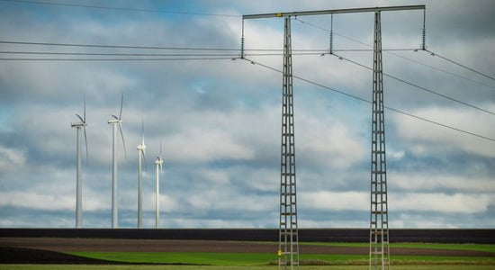 Vindkraftverk och elledningar som st&aring;r p&aring; en &aring;ker