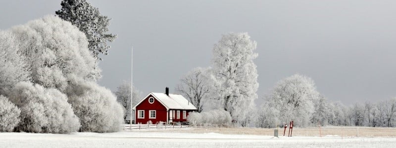 En r&ouml;d stuga i vinterlandskap.