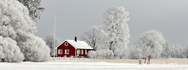 En r&ouml;d stuga i vinterlandskap.